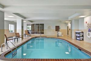 康威康威希尔顿花园酒店的酒店大堂的游泳池,配有椅子和桌子