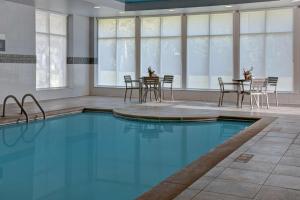 堪萨斯城希尔顿花园酒店堪萨斯城/堪萨斯州的一个带椅子和桌子的房间的游泳池