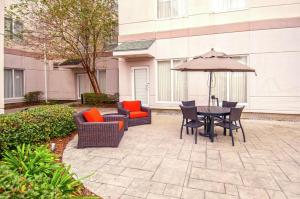 肯纳新奥尔良机场希尔顿花园酒店的庭院配有桌椅和遮阳伞。