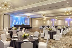新奥尔良新奥尔良会议中心汉普顿酒店及套房的宴会厅配有桌子、白色椅子和吊灯