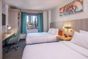 纽约纽约/曼哈顿切尔西希尔顿花园酒店的酒店客房设有两张床、一张书桌和一个窗户。
