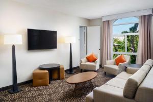 奥克兰奥克兰希尔顿机场酒店的客厅配有沙发、椅子和电视