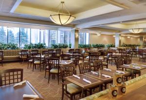 奥马哈奥马哈市中心希尔顿逸林酒店及商务会议中心的用餐室设有桌椅和窗户。