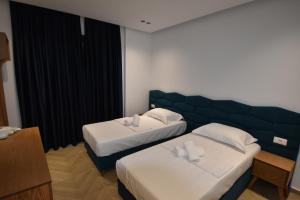 卡萨米尔Agimi Hotel的酒店客房设有两张床和蓝色床头板