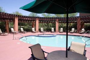 凤凰城菲尼克斯机场希尔顿花园旅馆的一个带桌子和遮阳伞的游泳池