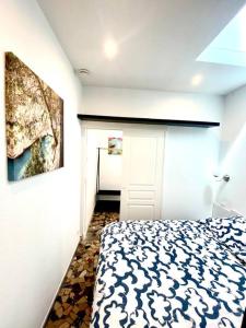 马赛Le Cabanon du Vallon des Auffes的卧室配有一张床,墙上挂有绘画作品