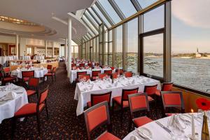 美因茨希尔顿美因茨酒店的餐厅设有白色桌子和红色椅子,窗户
