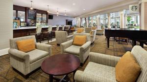 达拉姆三角研究园罗利达勒姆机场希尔顿逸林酒店的大堂设有椅子、钢琴和酒吧
