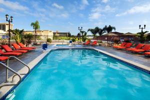 安纳海姆阿纳海姆希尔顿双树套房度假酒店&会议中心的度假村内带红色躺椅的大型游泳池