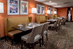 伍德森特瑞斯圣路易斯机场希尔顿酒店的用餐室配有桌椅,墙上挂有图片