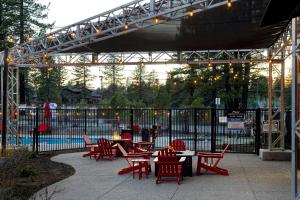 特拉基Hampton Inn & Suites Tahoe-Truckee的一个带红色桌椅的庭院和围栏