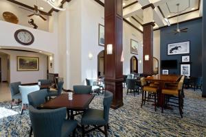 惠灵顿惠灵顿汉普顿套房酒店的餐厅设有桌椅和墙上的时钟