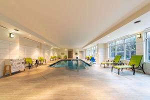 温彻斯特温彻斯特希尔顿花园酒店的一个带绿色椅子和桌子的房间的游泳池