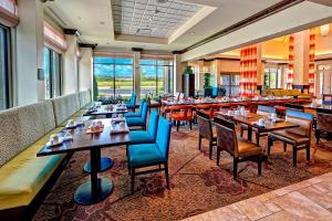 孟菲斯孟菲斯/孟菲斯沃尔夫卡瑟佳乐利希尔顿花园酒店的餐厅设有桌子和蓝色的椅子以及窗户。