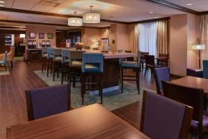 奥马哈奥马哈市中心区 - 阿克萨汉普顿酒店的一间带桌椅的餐厅和一间酒吧