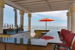 代托纳海滩代托纳海滩海滨希尔顿花园酒店的一个带桌子和遮阳伞的庭院和大海
