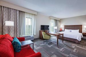 克莱尔莫尔克莱尔莫尔汉普顿酒店及套房的酒店客房,配有一张床和一张红色的沙发
