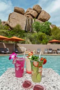 斯科茨Boulders Resort & Spa Scottsdale, Curio Collection by Hilton的坐在泳池旁的桌子上,喝上两杯鸡尾酒
