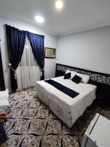麦加Najmat Alnoor Almaabdah Hotel的一间卧室配有一张带蓝色窗帘的大床