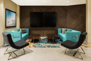 迈阿密迈阿密海豚购物中心希尔顿花园酒店的客厅配有2把蓝色椅子和平面电视