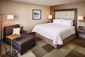Point Edward萨尼亚/爱德华点汉普顿酒店的配有一张床和一把椅子的酒店客房
