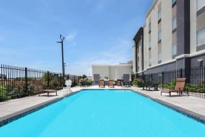 圣安东尼奥Hampton Inn & Suites San Antonio Brooks City Base, TX的一座带椅子的游泳池以及一座建筑