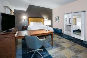 圣安东尼奥Hampton Inn & Suites San Antonio Brooks City Base, TX的酒店客房配有一张床和一张书桌及一台电视