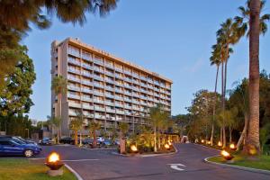 圣地亚哥拉霍亚希尔顿Curio Collection酒店的棕榈树停车场内的大型建筑
