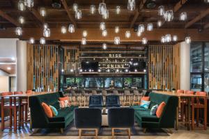 盖恩斯维尔盖恩斯维尔希尔顿逸林酒店的一间设有绿色椅子的餐厅和一间酒吧