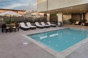 洛杉矶加利福尼亚州洛杉矶/好莱坞汉普顿酒店及套房的一个带椅子和桌子的游泳池以及一把遮阳伞