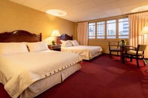 拉巴斯El Rey Palace Hotel的酒店客房设有两张床和一张桌子。