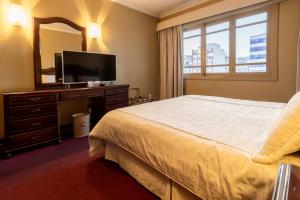 拉巴斯El Rey Palace Hotel的一间卧室配有一张床、镜子和电视