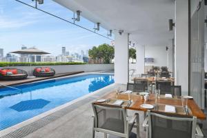 新加坡Hilton Garden Inn Singapore Serangoon的户外用餐区设有游泳池、桌子和椅子