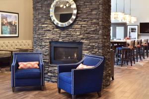 威斯康星戴尔Hampton Inn and Suites at Wisconsin Dells Lake Delton的两把蓝色椅子坐在壁炉前
