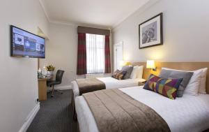 伦敦Thistle London Bloomsbury Park的酒店客房设有两张床和一台平面电视。