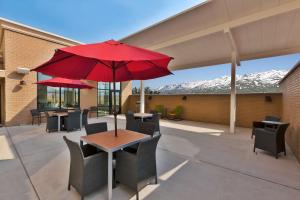 韦尔斯Hampton Inn & Suites Wells, Nv的庭院配有带红色遮阳伞的桌子