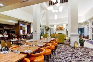 萨利纳Hilton Garden Inn Salina的配有木桌和橙色椅子的餐厅