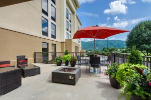 Covington维吉尼亚州卡温顿汉普顿酒店的一个带红色遮阳伞和桌椅的庭院