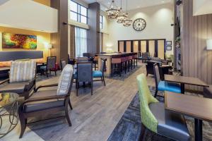 摩根敦Hampton Inn & Suites Morgantown / University Town Centre的餐厅设有桌椅和墙上的时钟