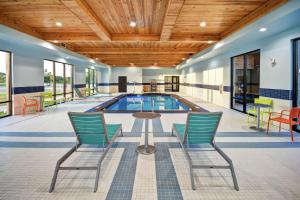 俄克拉何马城Home2 Suites By Hilton Oklahoma City Airport的一个带桌椅的泳池间和一个游泳池