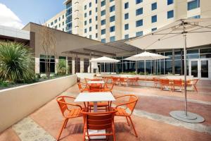 圣安东尼奥Embassy Suites By Hilton San Antonio Landmark的一个带桌椅和遮阳伞的户外庭院。