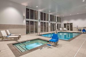 赫斯特Hilton Garden Inn Dallas At Hurst Conference Center的大楼内带蓝色椅子的游泳池