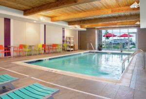 印第安纳波利斯印第安纳波利斯格林伍德希尔顿欣庭套房酒店的一座带椅子和桌子的酒店游泳池