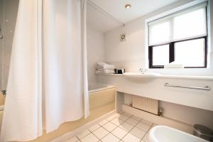 康威格鲁斯旅馆的白色的浴室设有淋浴帘和水槽