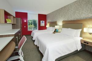 莫比尔Home2 Suites by Hilton Mobile I-65 Government Boulevard的红色墙壁的酒店客房内的两张床