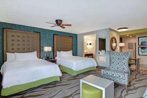 萨凡纳Homewood Suites By Hilton Savannah Airport的酒店客房,配有两张床和椅子