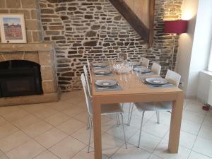 蓬托尔松Maison de ville située à 8 kms du Mont St Michel的一张带椅子的木桌和石头壁炉