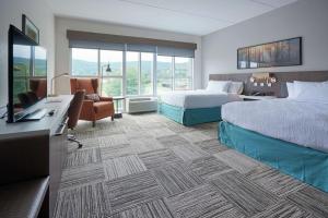 康宁Hilton Garden Inn Corning Downtown的酒店客房配有两张床和一张书桌
