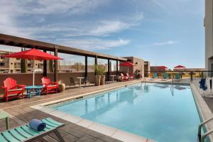 圣安东尼奥Home2 Suites By Hilton San Antonio North Stone Oak的一个带椅子和遮阳伞的游泳池