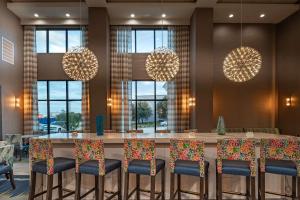 普莱诺Hampton Inn & Suites Dallas/Plano Central的大堂设有一张带椅子和灯的大桌子。